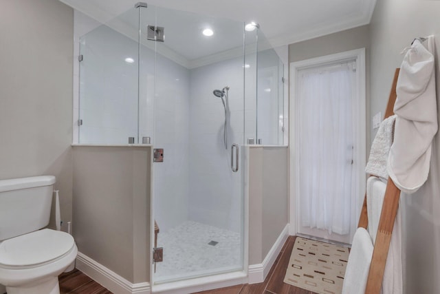 bathroom with toilet, a shower with door, and ornamental molding