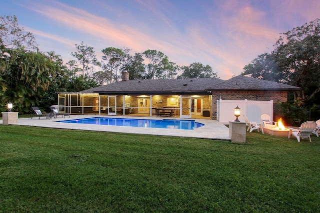 pool at dusk with a lawn, a patio, and a fire pit