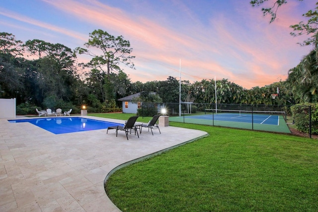 pool at dusk featuring a yard