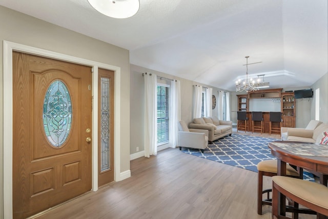 entryway with a chandelier, vaulted ceiling, and hardwood / wood-style flooring