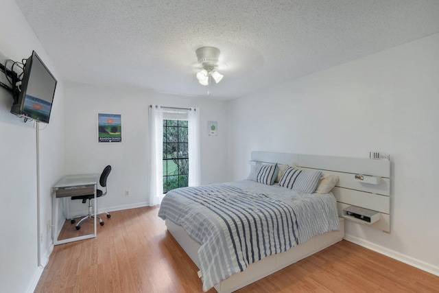 bedroom with ceiling fan, light hardwood / wood-style floors, and a textured ceiling