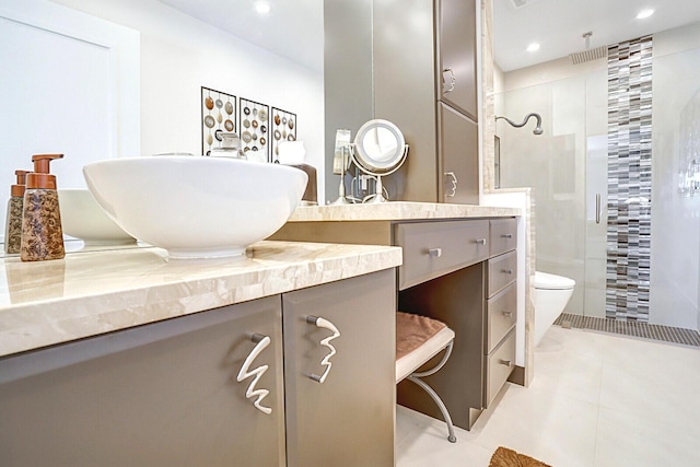 bathroom with a shower with door, toilet, vanity, and tile patterned flooring