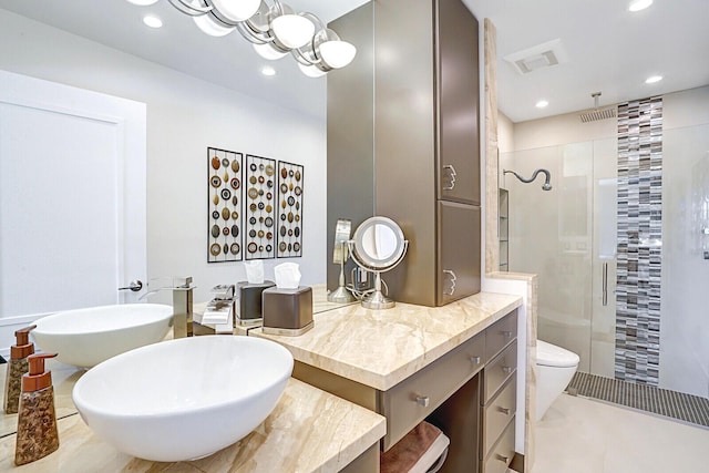 bathroom featuring toilet, vanity, tile patterned floors, and a shower with door