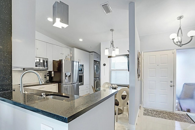 kitchen featuring stacked washer and dryer, white cabinetry, kitchen peninsula, appliances with stainless steel finishes, and decorative light fixtures