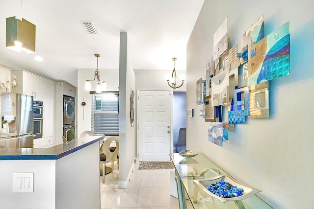 6140 Kings Gate Cir, Delray Beach, FL 33484 - foyer entrance featuring stacked washer / dryer, light tile patterned floors, a chandelier, and baseboards