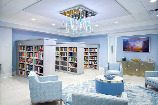 6140 Kings Gate Cir, Delray Beach, FL 33484 - living area featuring baseboards, wood finished floors, a chandelier, a drop ceiling, and bookshelves