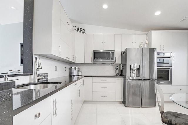 kitchen featuring appliances with stainless steel finishes, lofted ceiling, white cabinetry, and sink