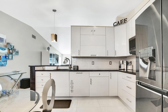 kitchen with decorative light fixtures, white cabinets, stainless steel fridge, and sink