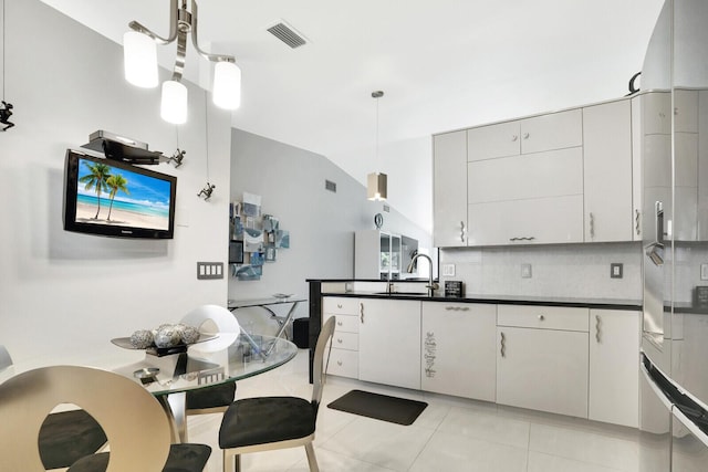 kitchen featuring white cabinets, backsplash, hanging light fixtures, vaulted ceiling, and light tile patterned floors