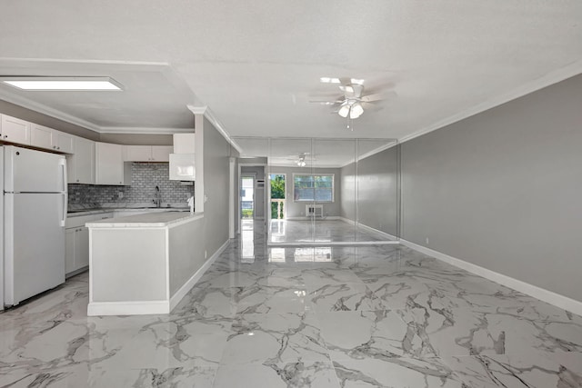 kitchen featuring ceiling fan, tasteful backsplash, white fridge, white cabinets, and ornamental molding