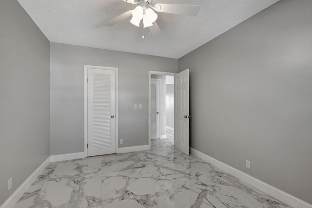 unfurnished bedroom with ceiling fan, a textured ceiling, and a closet