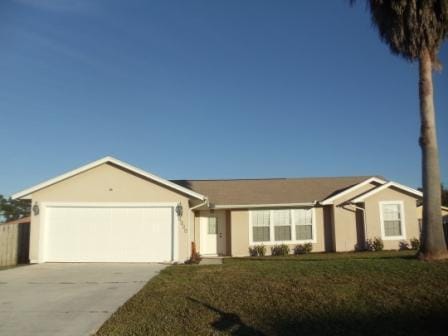 ranch-style house with a garage and a front lawn