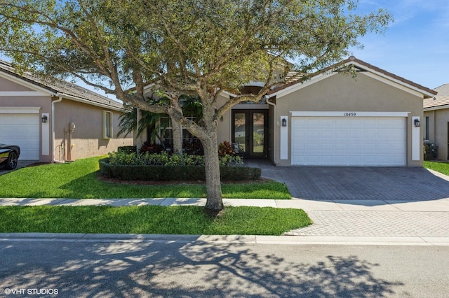 view of front facade featuring a garage, french doors, decorative driveway, and stucco siding