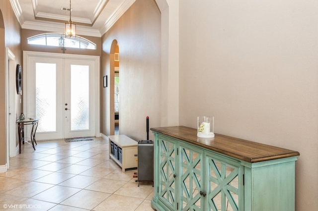 entryway featuring light tile patterned floors, arched walkways, a tray ceiling, crown molding, and french doors