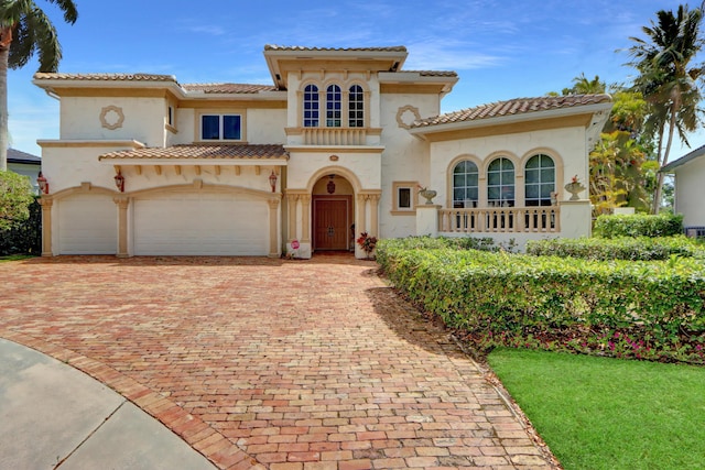 mediterranean / spanish house with stucco siding, decorative driveway, and a tile roof