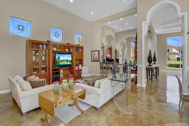 living room featuring baseboards, arched walkways, a high ceiling, and recessed lighting