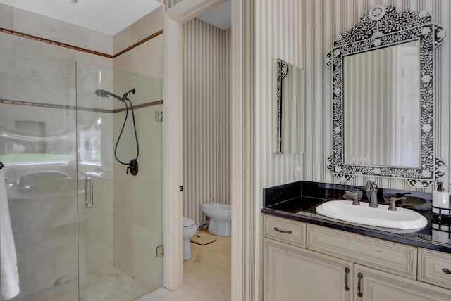 bathroom with a shower stall, vanity, tile patterned floors, toilet, and wallpapered walls