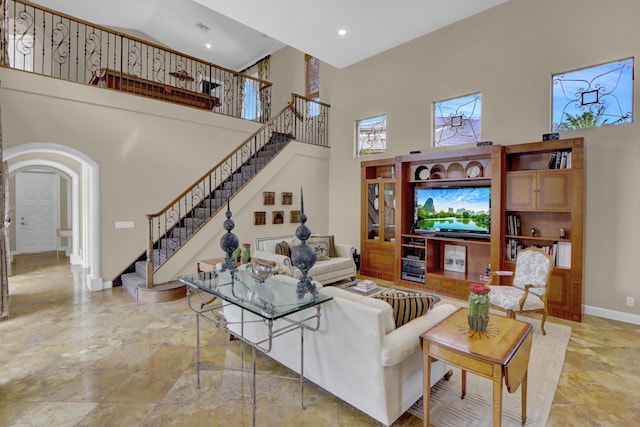 living area featuring a high ceiling, arched walkways, stairs, recessed lighting, and baseboards