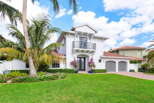 mediterranean / spanish-style home with a balcony, a garage, french doors, and a front yard