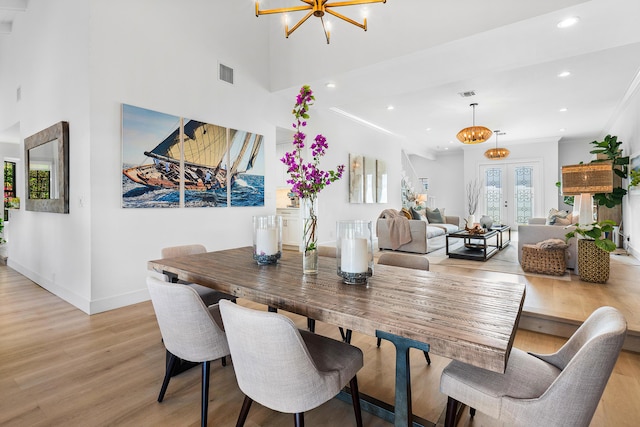 dining area featuring crown molding, light hardwood / wood-style flooring, french doors, and a notable chandelier