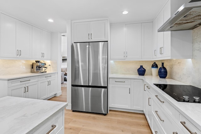 kitchen with backsplash, stainless steel fridge, black electric stovetop, and wall chimney range hood