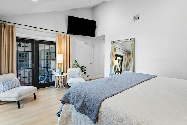 bedroom with hardwood / wood-style floors, high vaulted ceiling, and french doors