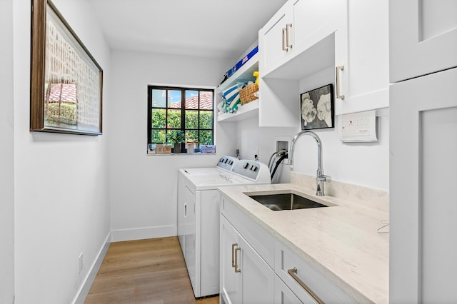 washroom featuring cabinets, washing machine and dryer, light wood-type flooring, and sink