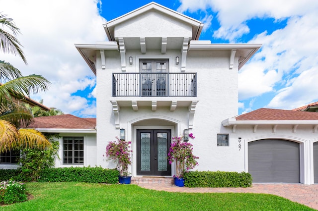 view of front of property with french doors, a balcony, a garage, and a front lawn