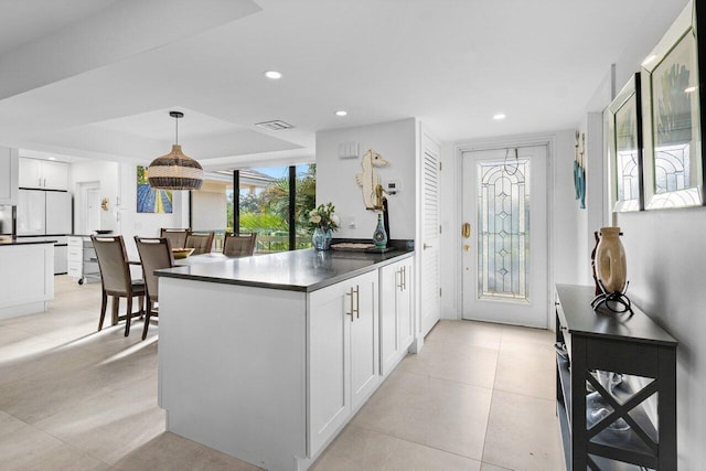 kitchen with a tray ceiling, white cabinetry, pendant lighting, and white refrigerator