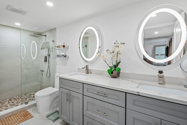 bathroom featuring tile patterned floors, vanity, a tile shower, and toilet