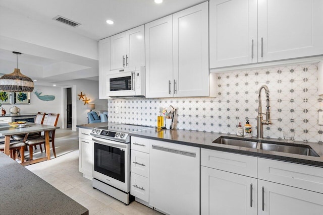 kitchen with sink, tasteful backsplash, pendant lighting, white appliances, and white cabinets