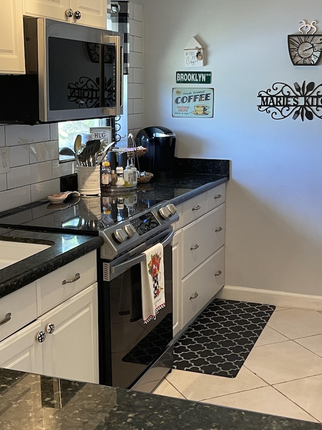 kitchen with white cabinets, light tile patterned floors, appliances with stainless steel finishes, and tasteful backsplash