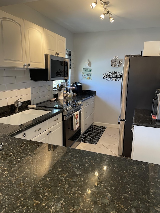 kitchen featuring sink, decorative backsplash, light tile patterned floors, white cabinetry, and stainless steel appliances