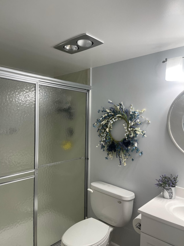 bathroom featuring vanity, toilet, and a shower with door