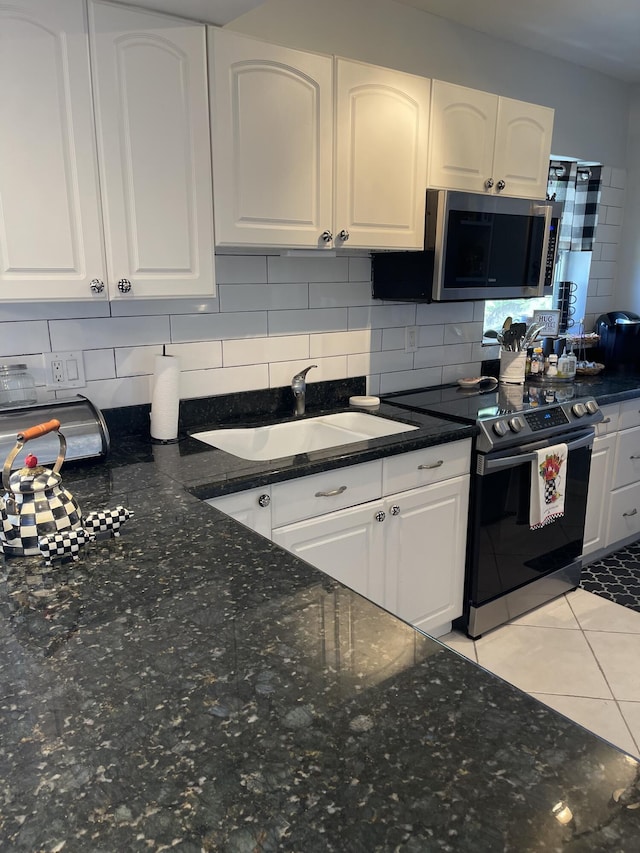 kitchen featuring appliances with stainless steel finishes, backsplash, sink, white cabinets, and light tile patterned flooring