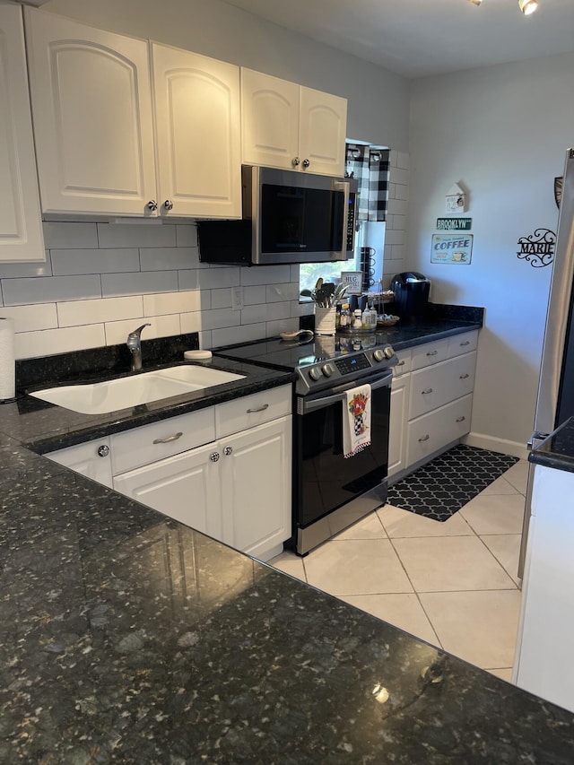 kitchen featuring tasteful backsplash, stainless steel appliances, sink, light tile patterned floors, and white cabinetry