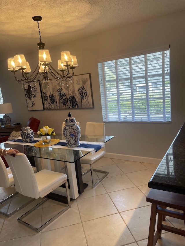 tiled dining space with a chandelier and a textured ceiling