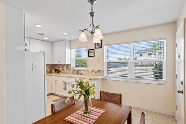 tiled dining room featuring a chandelier, a healthy amount of sunlight, and sink