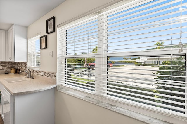 interior space featuring tasteful backsplash, white cabinetry, a healthy amount of sunlight, and sink