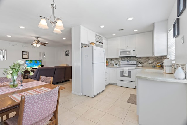 kitchen with white cabinetry, sink, decorative light fixtures, and white appliances