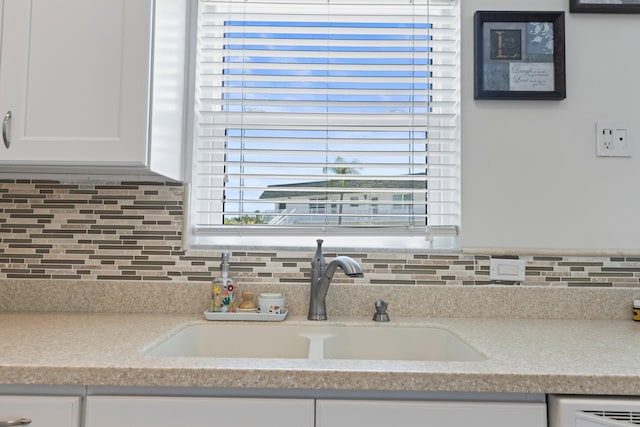 details featuring white cabinetry, sink, and tasteful backsplash