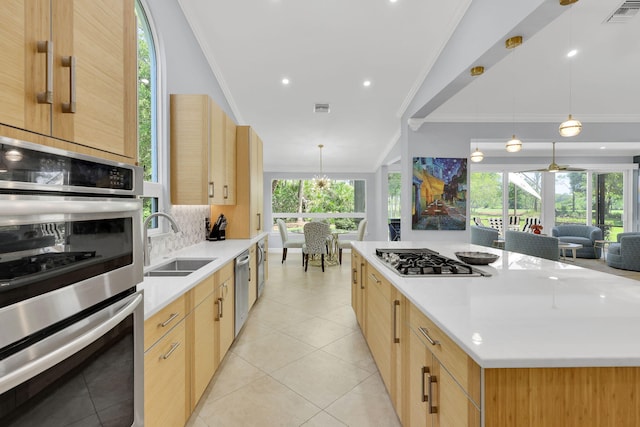 kitchen with pendant lighting, sink, ornamental molding, and stainless steel appliances