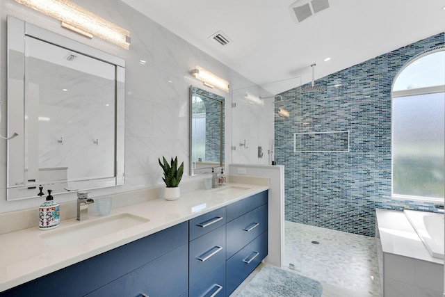 bathroom with tiled shower, vanity, tile walls, and lofted ceiling