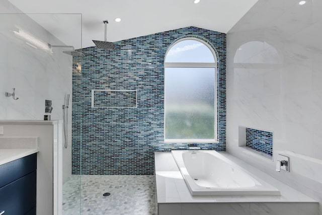 bathroom featuring vanity, lofted ceiling, tile walls, and independent shower and bath