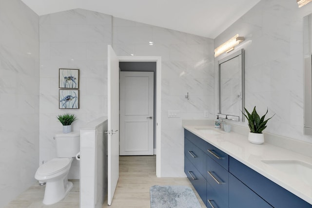 bathroom featuring vanity, toilet, tile walls, and vaulted ceiling