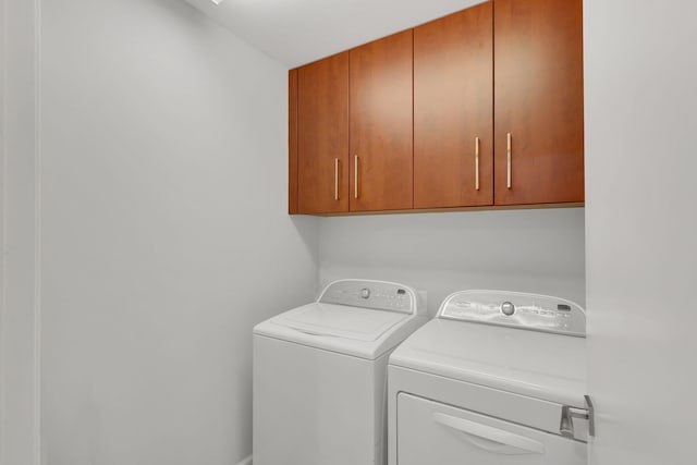 clothes washing area featuring cabinets and washing machine and dryer