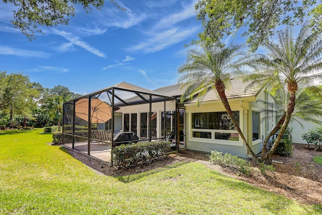 back of house with glass enclosure and a lawn