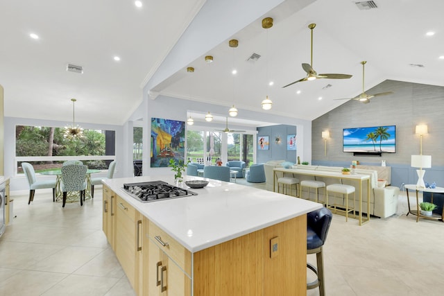 kitchen with vaulted ceiling, ceiling fan, light brown cabinets, stainless steel gas stovetop, and a large island