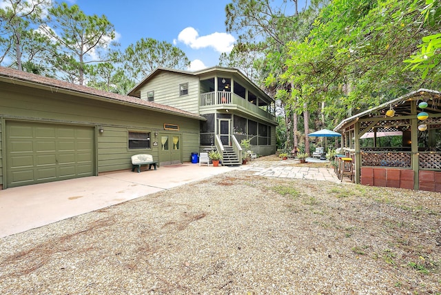 back of house with a gazebo, a sunroom, a garage, and a balcony