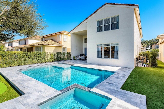 back of house featuring a patio, a lawn, and a pool with hot tub